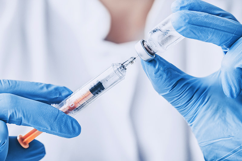 Doctor preparing a travel vaccine injection with a syringe and vial.